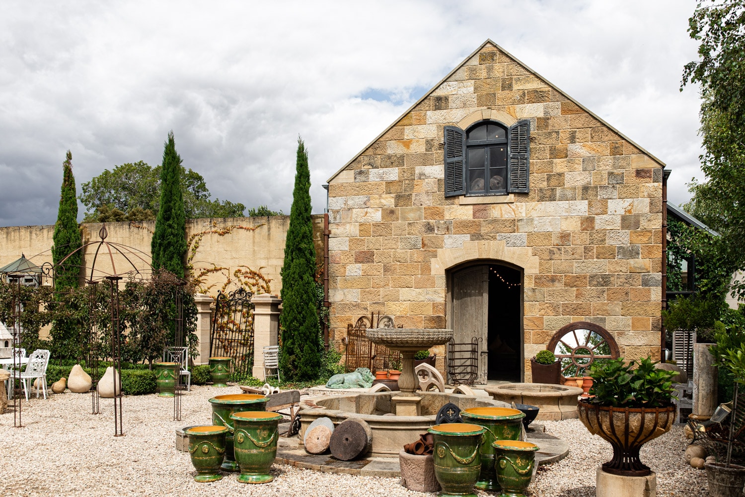 Jardin Room courtyard with stone building and French garden urns in Oatlands